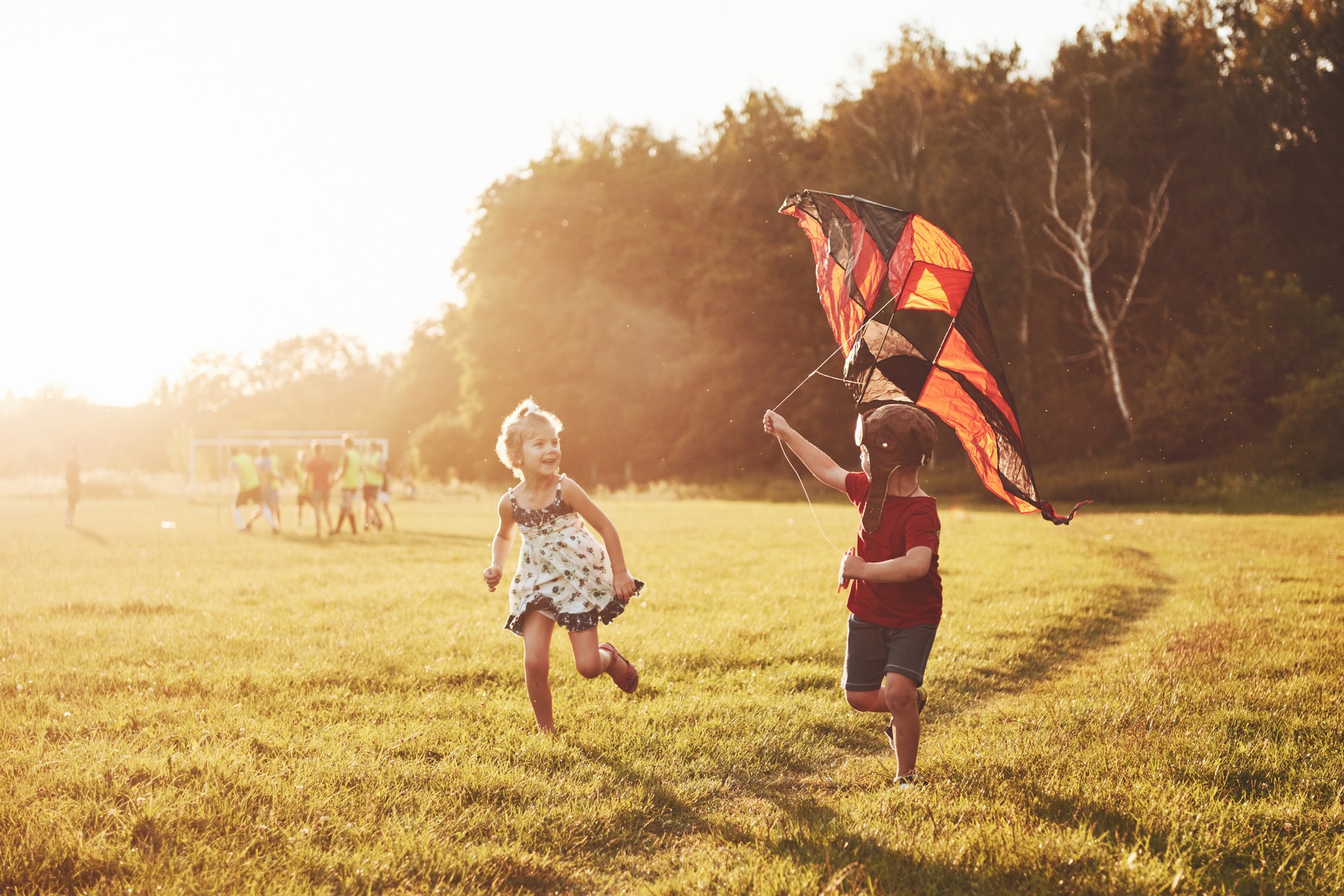 Happy children launch a kite in the field at sunset. Little boy and girl on summer vacation